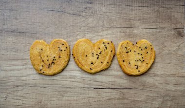 Kahverengi kelebek çıtır ekmek puf böreği. Kahverengi ahşap masada siyah susam soslu.