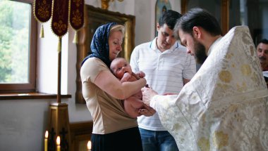 Vaftiz ayini. Bebeği vaftiz etmek. Çocuk, rahip ve kilise cemaati.