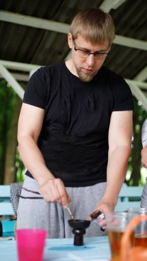 Siyah gömlekli orta yaşlı adam nargile yapıyor.