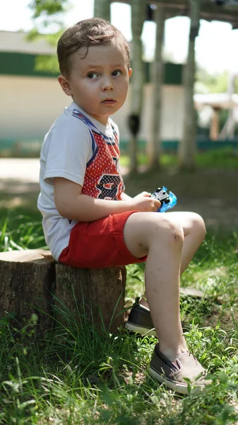 Μικρό αγόρι που κάθεται στο κούτσουρο στην παιδική χαρά — Φωτογραφία Αρχείου