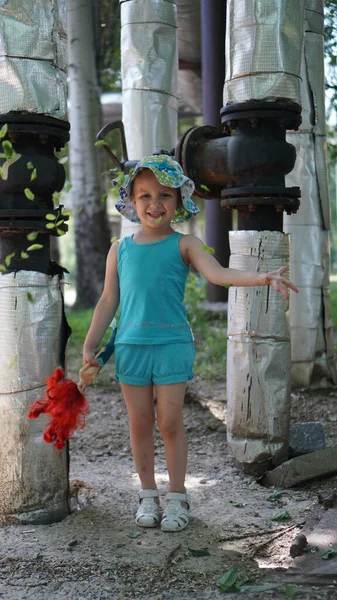 Portret van een klein meisje in blauw pak tussen verwarmingsbuizen — Stockfoto