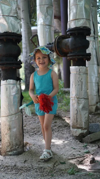 Portret van een klein meisje in blauw pak tussen verwarmingsbuizen — Stockfoto