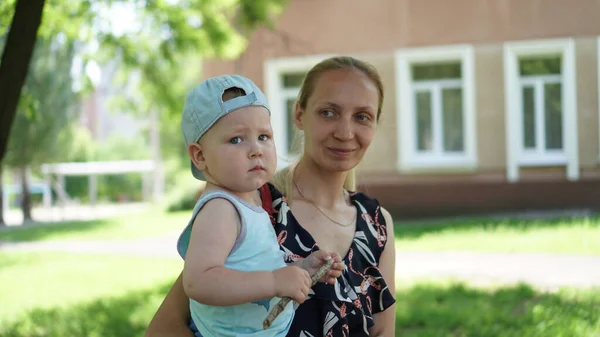 Petit garçon en T-shirt bleu et sa mère sur la pelouse dans le parc — Photo