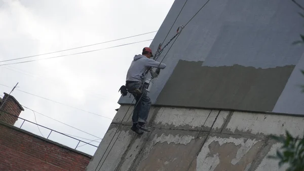 Isolering av husväggar. Arbetare som hänger på repen installerar värmesköld — Stockfoto