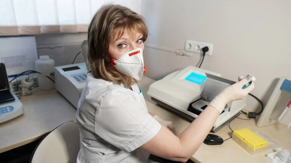 Coronavirus 'tan gelen kırmızı kapakçık solunum cihazına sahip bir tıbbi laboratuvar teknisyeninin portresi. - Evet. Pipeti tutan laboratuvar teknisyeni kan örneklerini test ediyor.