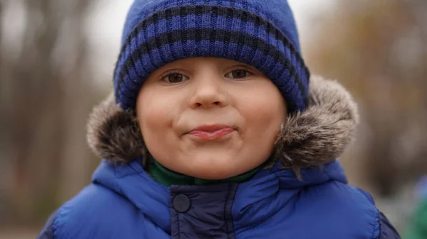 一个戴着白蓝色针织帽子的可爱小男孩的滑稽画像 小孩鬼鬼祟祟 — 图库照片