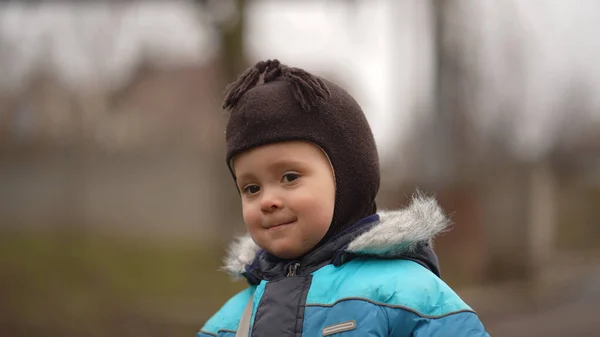 Portret Małego Uśmiechniętego Chłopca Niebieskiej Kurtce Brązowej Czapeczce Parku — Zdjęcie stockowe