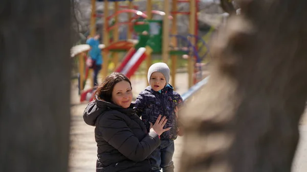 Beautiful Mom with cute little son in playground in spring. Concept of happy family and spring