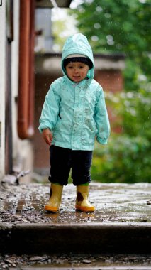 Yağmurdan sonra kapüşonunda kirli bir yüzü olan komik bir çocuğun portresi.