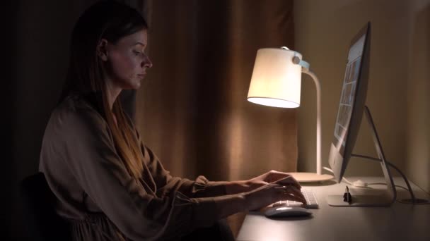 Güzel genç kadın masasında oturuyor ve bir bilgisayar üzerinde çalışıyor. — Stok video