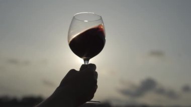 4 bin. Bir kadın gün batımında elinde bir bardak kırmızı şarap tutuyor.. 