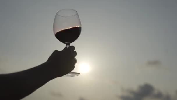 4K. Una mujer sostiene una copa de vino tinto al atardecer. — Vídeos de Stock