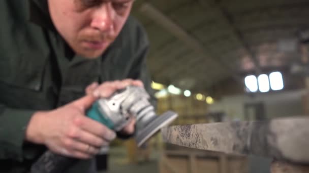 Portrait of a serious worker polishing a dark marble table in a factory. Wide angle. Subject moves out of focus to focus. Super Slow Motion — Stock Video