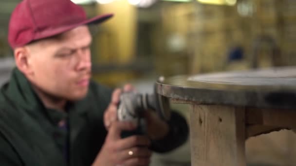 Portrait of a serious worker in green jacket polishing a dark marble table in a factory. Wide angle. Camera moves out of focus to focus. Super Slow Motion — Stock Video