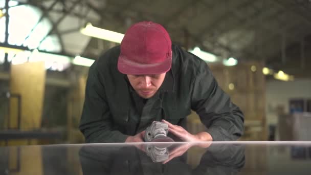 Portrait of a serious worker in a green jacket polishing a dark marble table in a factory. Still frame. Super Slow Motion — Stock Video