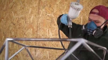 İşçi Metal Ürünleri Havasız Spreyle Boyuyor. Kamera konunun etrafında döner. Yavaş çekim