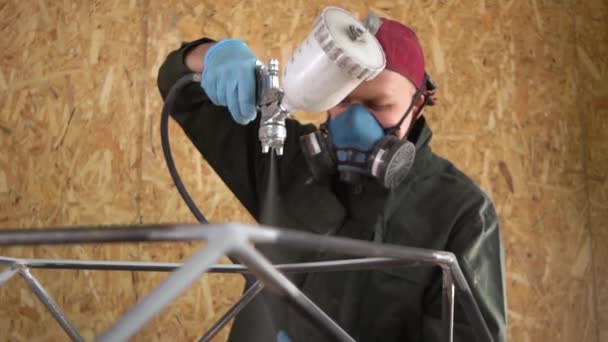 Arbeiter mit roter Mütze und grüner Jacke bemalt Metallprodukte mit Airless-Spray. Zeitlupe — Stockvideo