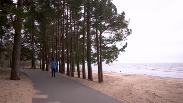 Mujer Camina a lo largo del camino a lo largo del mar frío — Vídeos de Stock