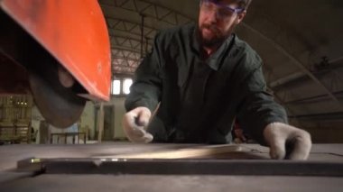  Bir işçi, testereyle kestiği metal bir parçayı alır. Yavaş çekim