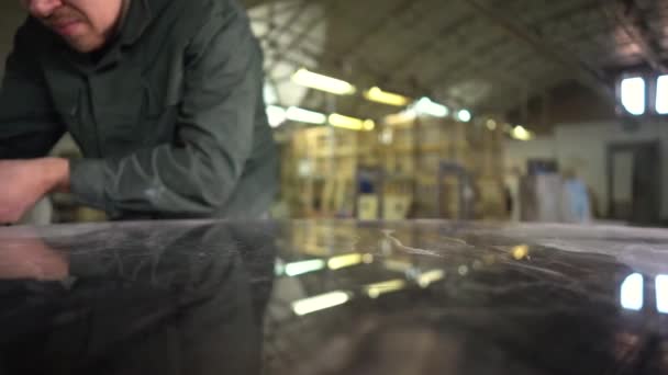 Travailler en Europe dans une veste verte polit une table en marbre dans une usine. Sur la table en marbre le reflet des lampes. La caméra se déplace sur le curseur. Super ralenti — Video