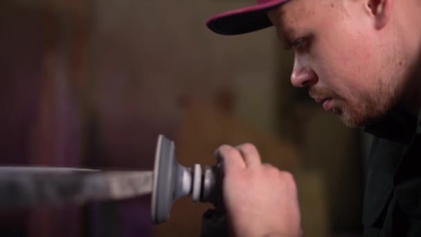 Portrait of a serious worker in a green jacket and purple cap polishing a dark marble table. Still frame. Super Slow Motion — Stock Video