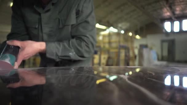 緑のジャケットの認識できない労働者は、工場内の大理石のテーブルを研磨します。大理石のテーブルの上にランプの反射。カメラはスライダーで動きます。超スローモーション — ストック動画