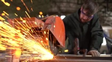 Metal işçisi bir atölyede çalışırken elektrikli testereyle demir öğütüyor. Süper Yavaş Çekim