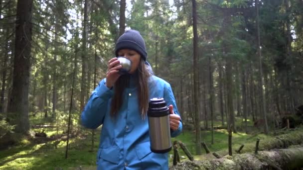 Mulher tendo descanso com bebida quente, chá de garrafa térmica sentado na árvore na floresta. Movimento lento — Vídeo de Stock