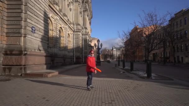 A man throws a frisbee against the background of a historic building and empty streets in St. Petersburg. Slow motion. — Stock Video