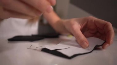 Evde dikiş dikmeden önce kumaş ve desenlerle çalışan genç bir kadın..