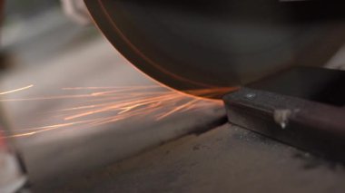 Profesyonel işçiler fabrikada metali dairesel testereyle kesiyor. Yavaş çekimde. Kamera testereyle hareket ediyor.