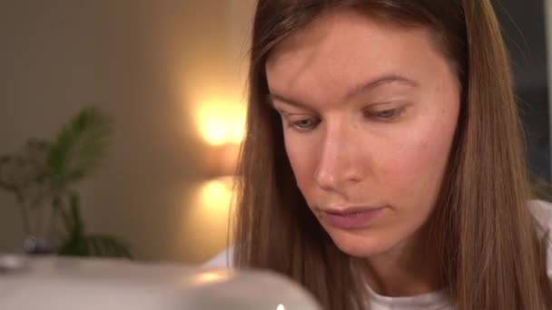 Ansiktet på en ung kvinna som syr på en symaskin. — Stockvideo