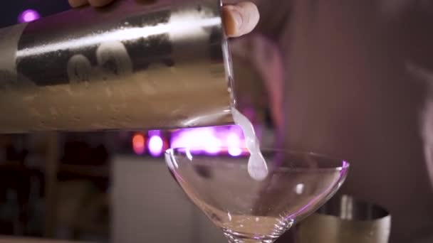 Rallentatore Primo piano della mano del barista che versa un cocktail da uno shaker in un bicchiere . — Video Stock