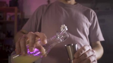 Barmen limon suyunu şişeden jigger 'a doldurur sonra da karıştırıcıya döker. Ağır çekim. Kamera nesneyi takip eder.
