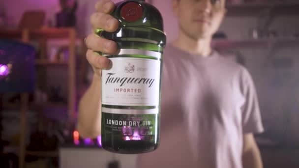 酒保拿起一瓶杜松子酒放在摄像机前的桌子上。摄像机跟在主题后面 — 图库视频影像