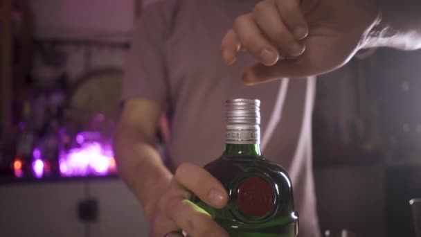 Slow motion close-up video toont een mannelijke hand draaien van een groene fles gin. — Stockvideo