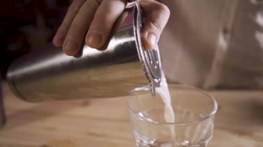 Yavaş çekim. Erkek eli, bardaktan bardağa kokteyl döküyor..