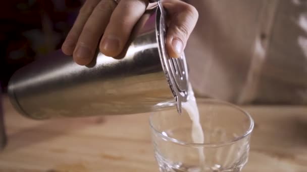 Zeitlupe Close up shot männliche Hand gießt einen Cocktail aus einem Shaker in ein Glas. — Stockvideo