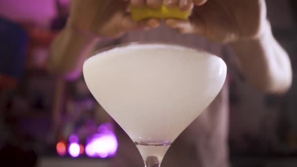 Barkeeper presst Zitronenschale in ein Glas mit einem französischen Cocktail 75 — Stockvideo