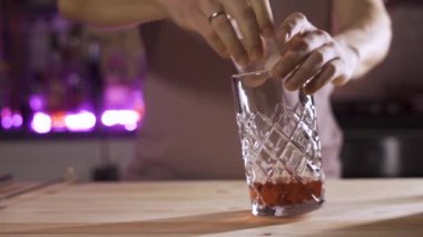 Yavaş çekimde iki buz küpü karıştırıcı bardağa düşer ve su sıçratır.