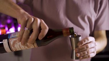 Barmenlerin elleri kırmızı vermutu şişeden jigger 'a döker. Yavaş çekim.