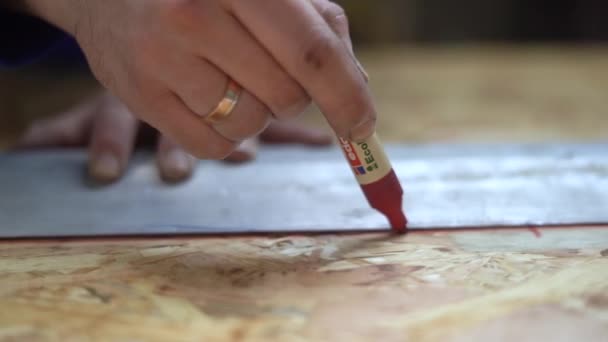 Handen van de mens met behulp van een Heerser om metingen te doen op een stuk hout. Rode viltstift — Stockvideo