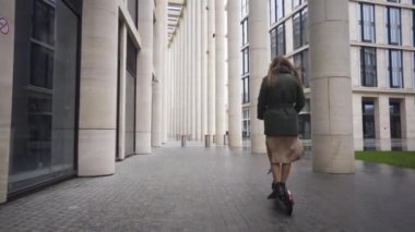  E-scooter sürücüsü, genç ve güzel bir kadın at paylaşımı ya da kişisel ekolojik taşıma aracı. Arka Görünüm