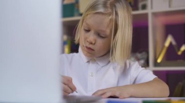 Karantina nedeniyle uzaktan öğrenme, online eğitim. Evde bilgisayardan öğrenen küçük bir çocuk.