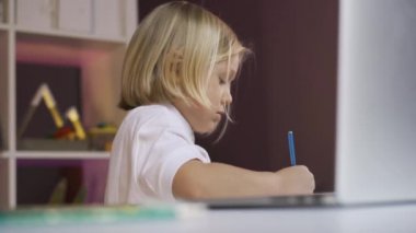 Uzaktan öğrenme çevrimiçi eğitim. Şirin bir okul çocuğu evdeki dizüstü bilgisayarından online ders çiziyor.