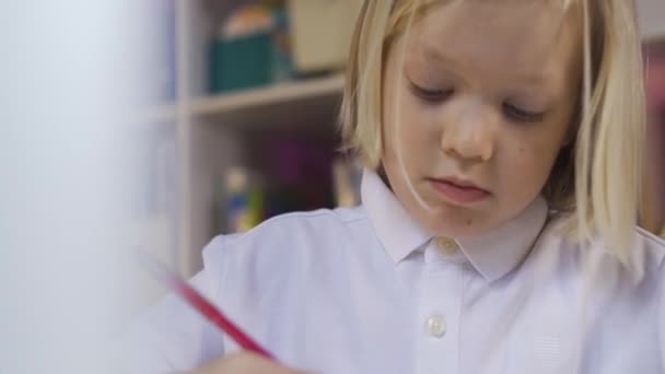 Educación a distancia en línea. Retrato de un lindo niño de escuela dibujando en una habitación para niños — Vídeos de Stock