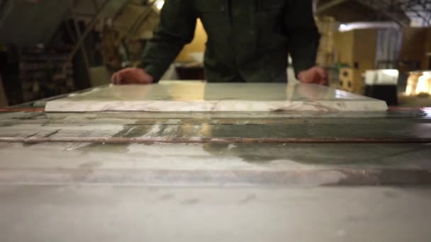 Worker loads a piece of white marble into a saw machine. Wide angle. Camera moves forward — Stock Video