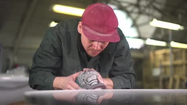 Рабочий в зеленой куртке полирует мраморный стол на заводе — стоковое видео