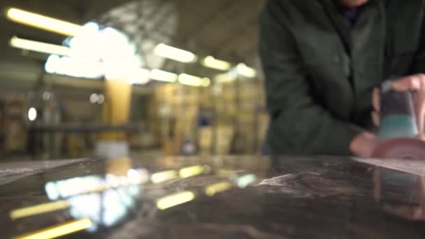 Trabajador irreconocible en una chaqueta verde pule una mesa de mármol en una fábrica. La cámara se mueve en el control deslizante. Super cámara lenta — Vídeos de Stock