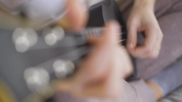 Cierra las manos jovencita tocando el ukelele en casa. Educación a distancia Educación en línea — Vídeos de Stock